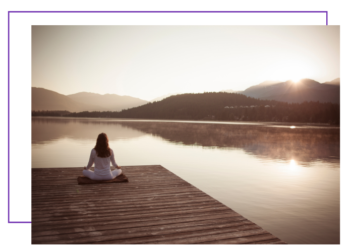 Eine Frau meditiert am See und verbindet sich mit der spirituellen Bedeutung der Engelzahl 999